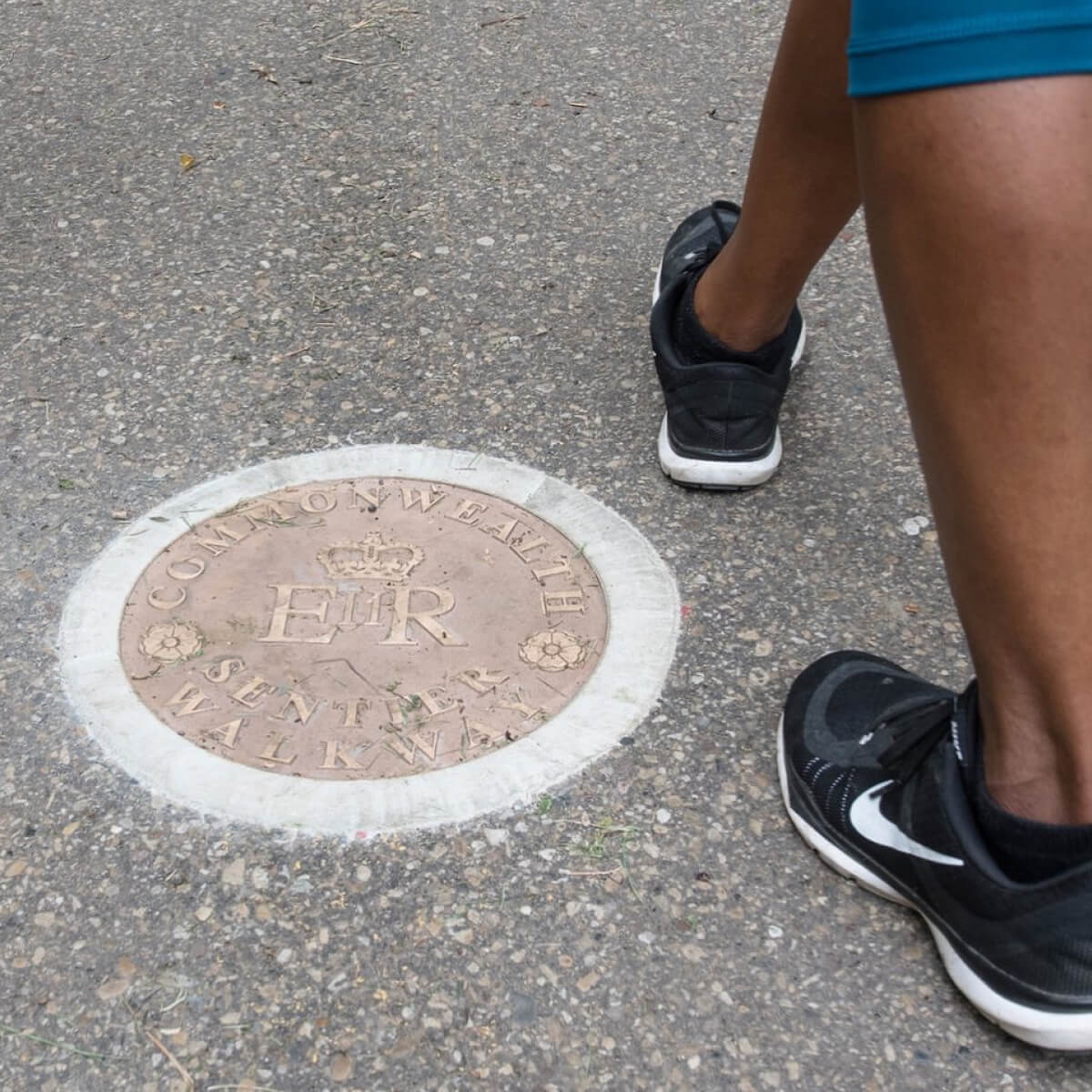 Photo of somebody walking near one of the physical Commonwealth Walkway medallions embedded in the ground