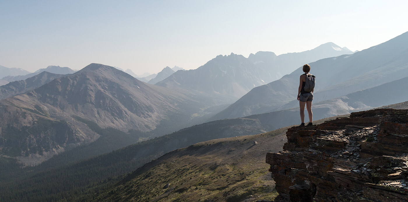 Imagery of a woman hiker enjoying the mountain view from ontop a cliff